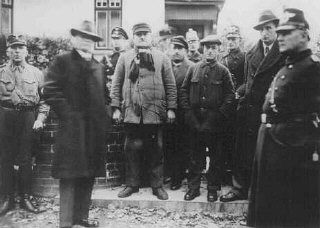 Jews arrested during Kristallnacht stand under guard before being deported to the Sachsenhausen concentration
